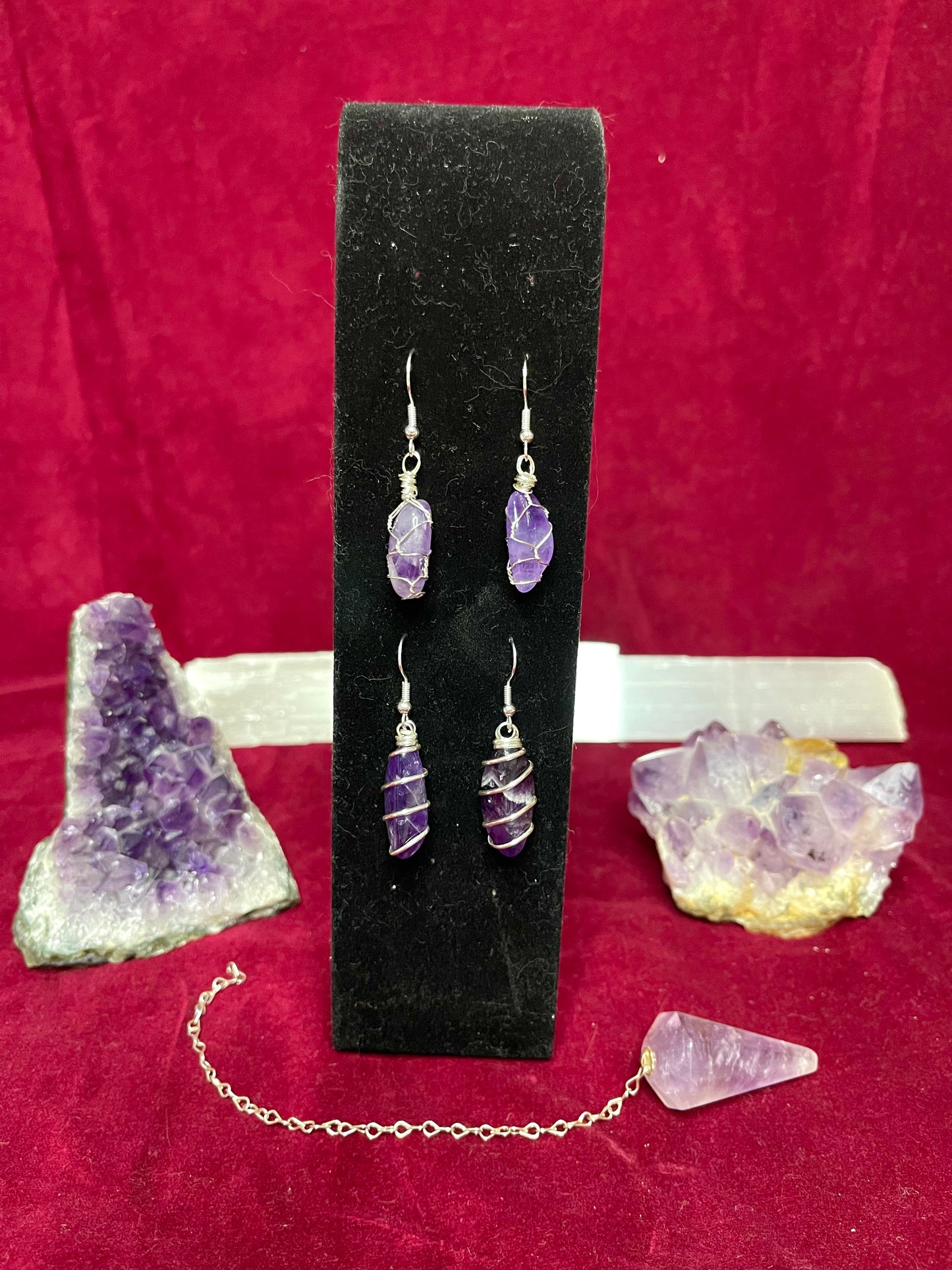 a pair of earrings with amethyst crystals on a chain